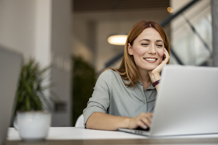 Smiling HR Woman Working Remotely on Laptop in Modern Workspace 4human HRM Integration with PowerOffice Go
