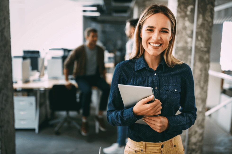 woman smiling holding a tablet in an office